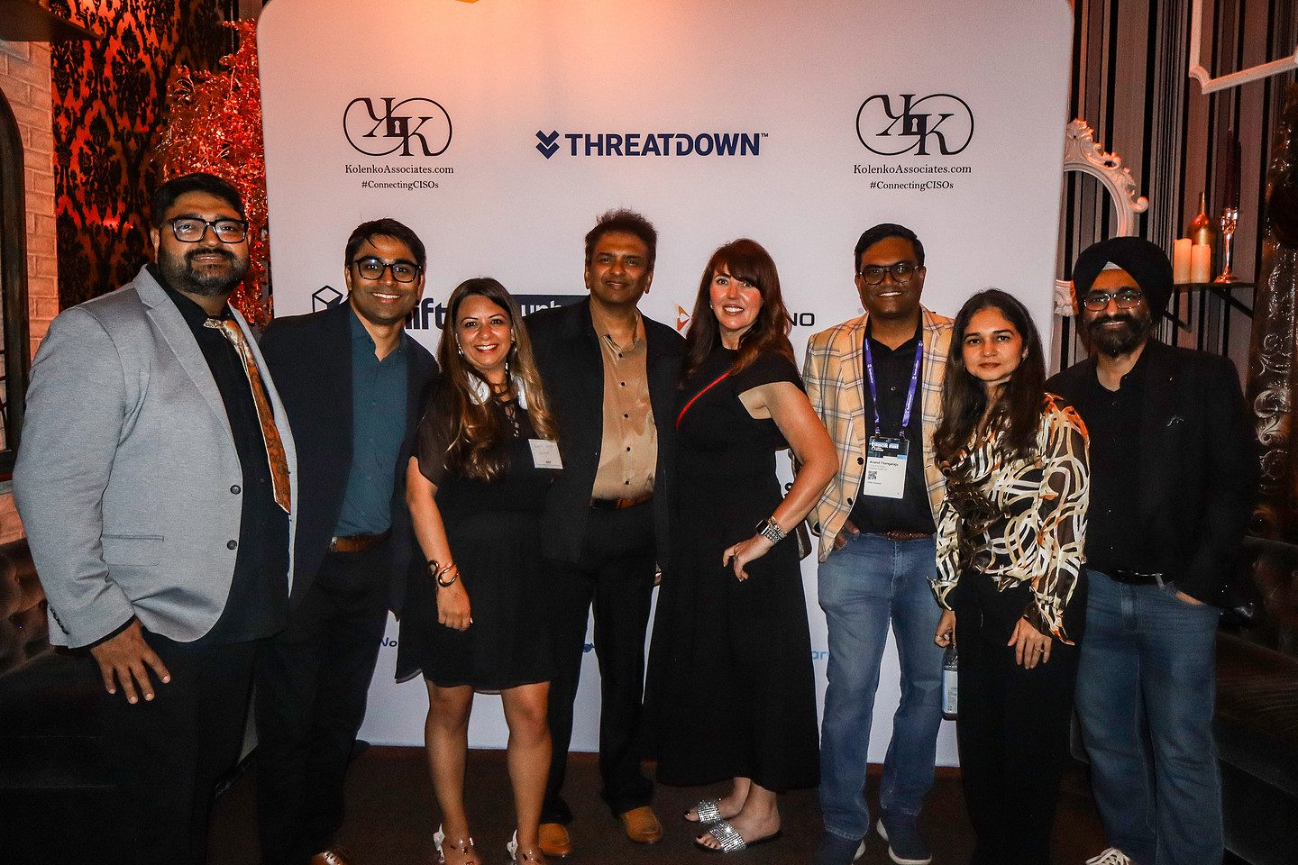 A large group of guests photographed together at the sponsor backdrop