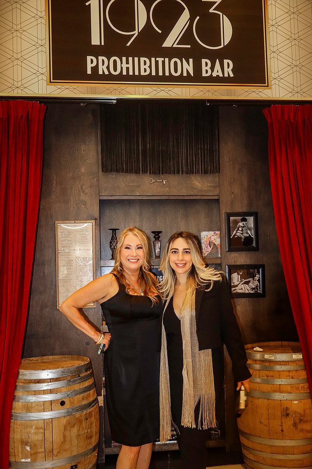 Two guests photographed against a deep red drape