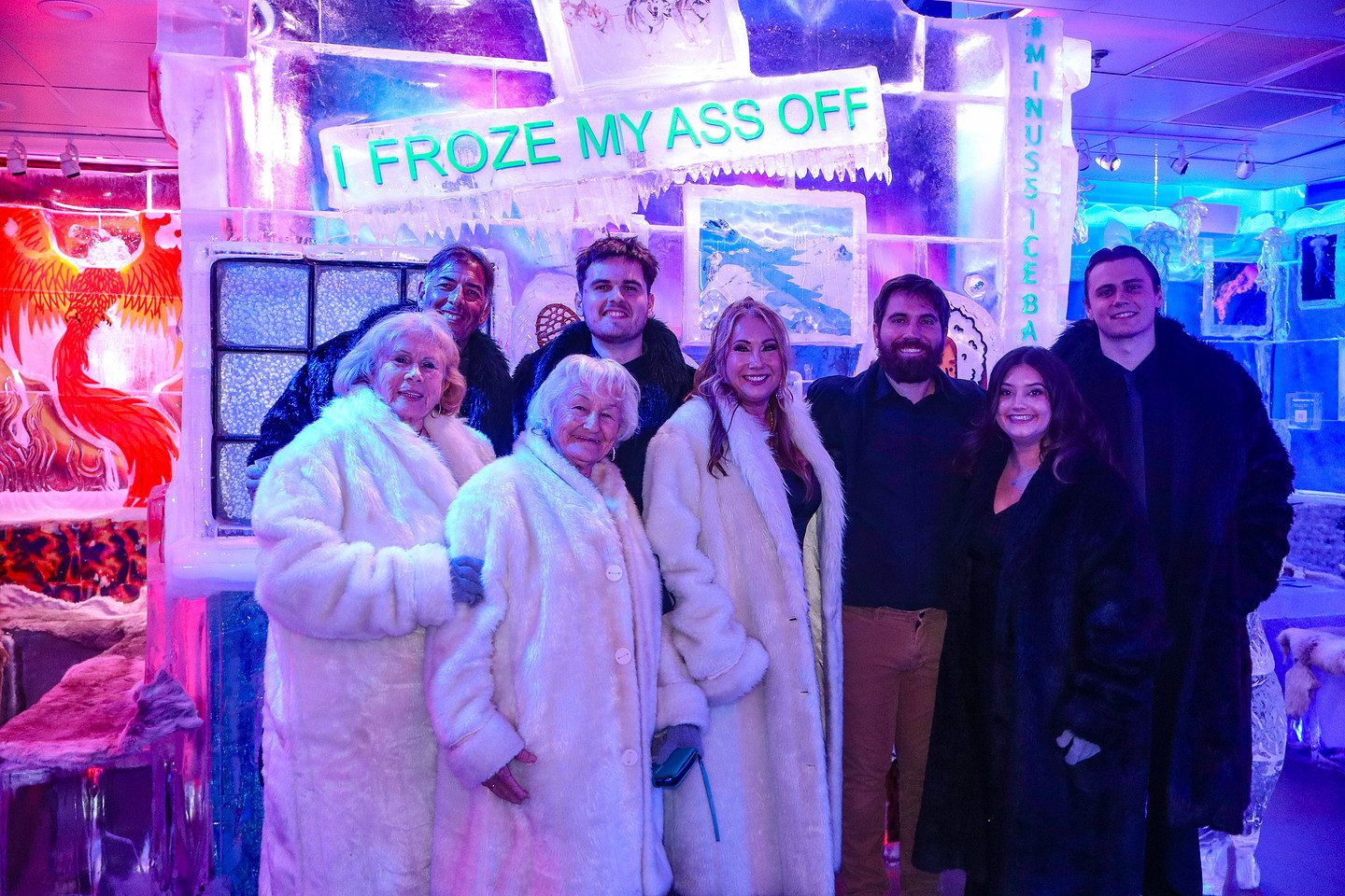 A group of guests in fur coats inside the neon-lit minus5 ICEBAR