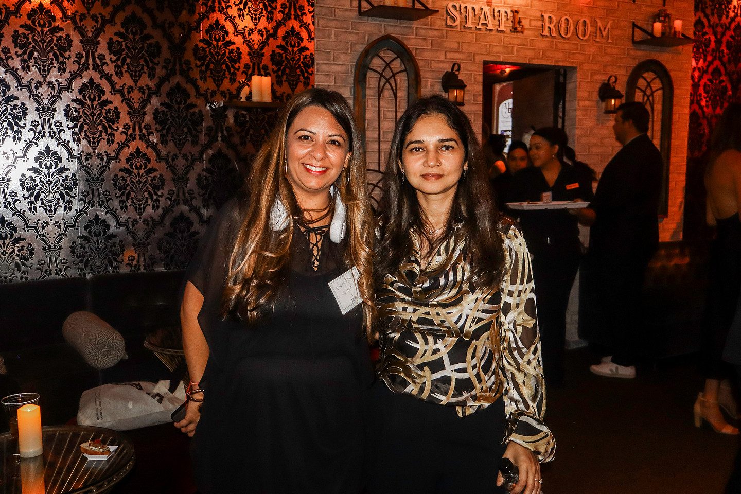Two guests photographed in the State Room against patterned wallpaper