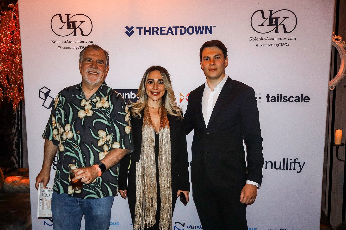 Three guests photographed together at the sponsor backdrop