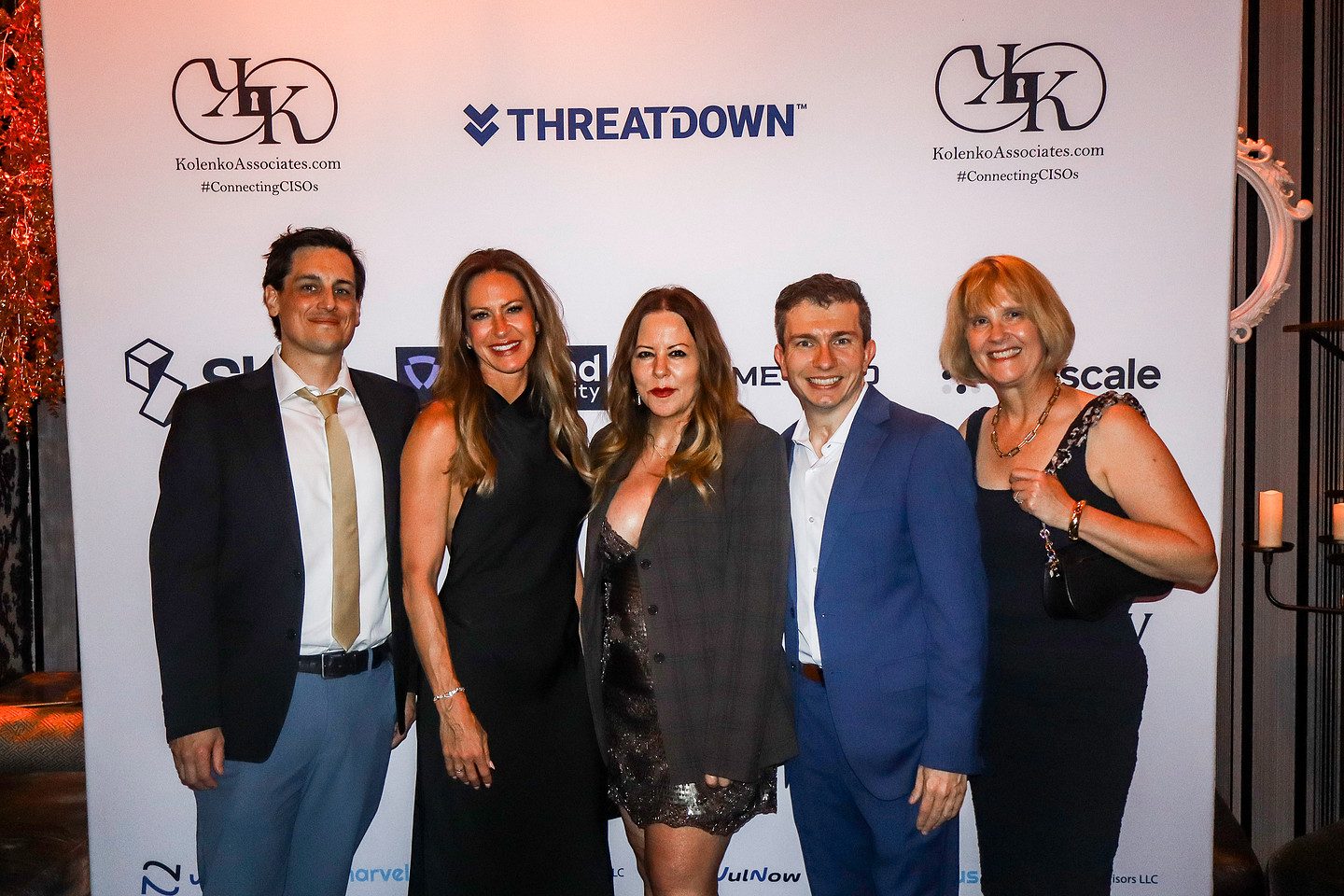 Five guests photographed together at the sponsor backdrop