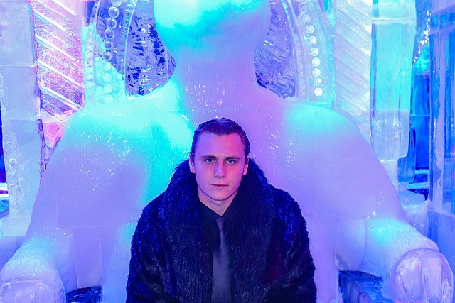 A guest in a fur coat seated on the carved ice throne