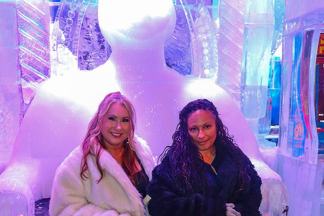 Two guests in fur coats seated on the carved ice thrones