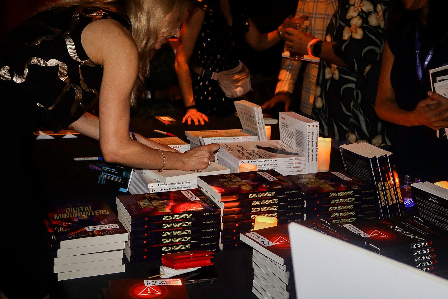 An author signing copies at a table stacked with books