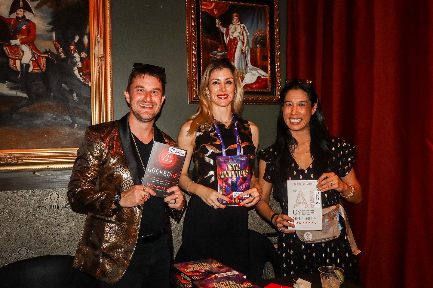 Three authors holding up their books at the Author Speakeasy