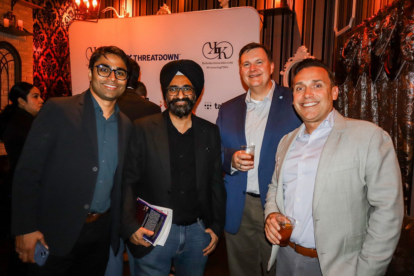 Four guests photographed together at the sponsor backdrop