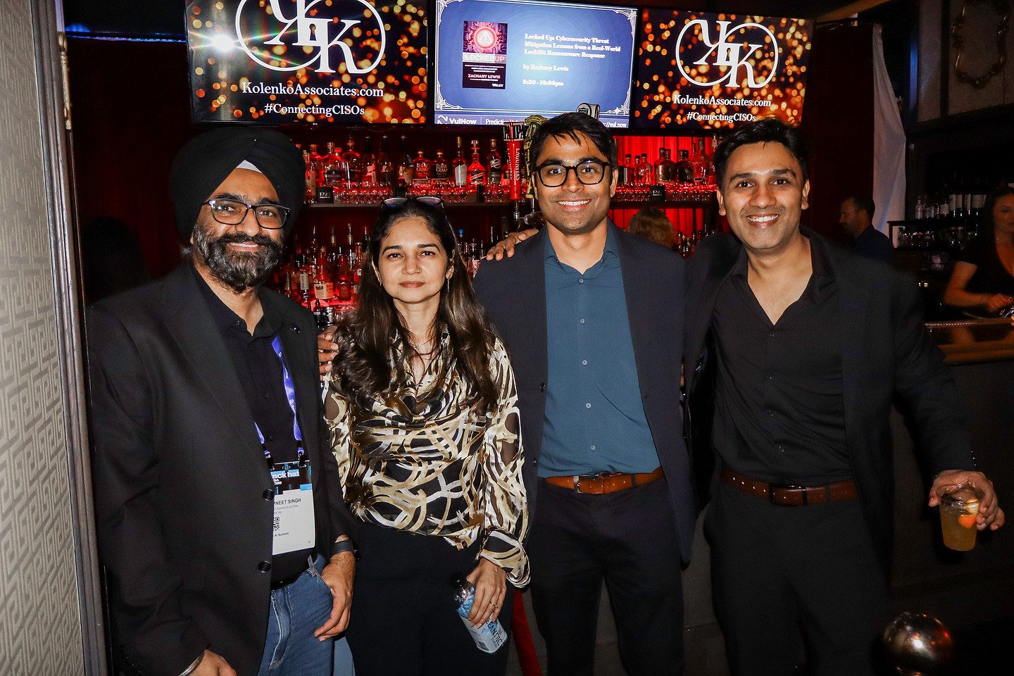 Four guests photographed together at the sponsor backdrop later in the evening
