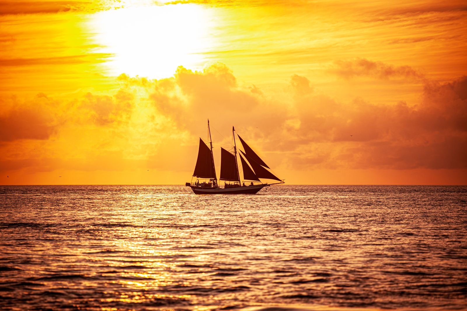 A three-masted sailing yacht under way at golden hour